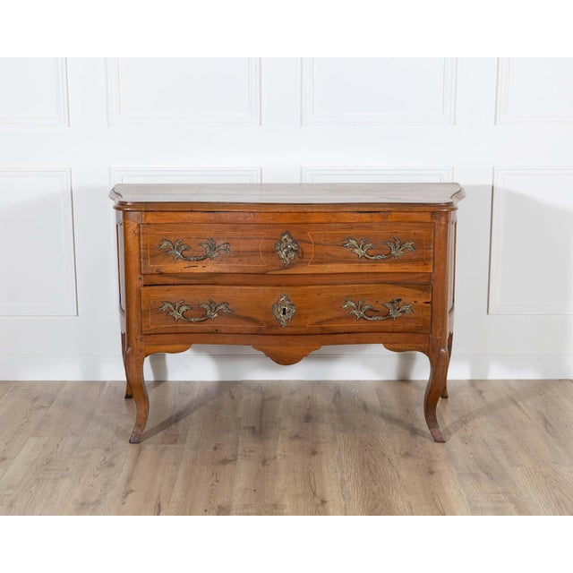 An elegant Louis XV period chest of drawers from the 18th century, crafted in solid walnut and distinguished by its...