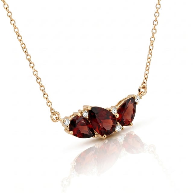 Indulge in the passionate radiance of deep red Garnet. This eye-catching necklace features a dramatic trio of pear-cut...