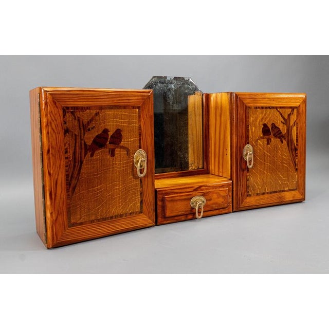 Art Deco wall cabinet with mirror and storage compartments, circa 1930s. Compact wall-mounted cabinet in wood with a warm-...