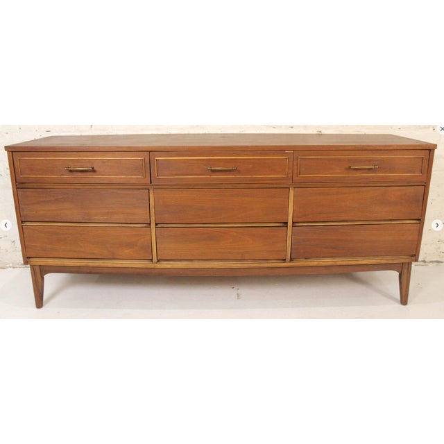 This is stunning nine drawer walnut dresser by Dixie Furniture Co.. This piece has warm honey color that compliments the...