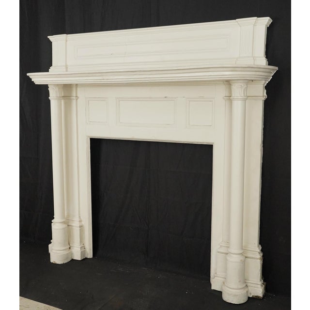 Colonial Revival wood mantle with rectangular frieze panels, a layered cornice shelf, and fluted pilasters. The mantle is...