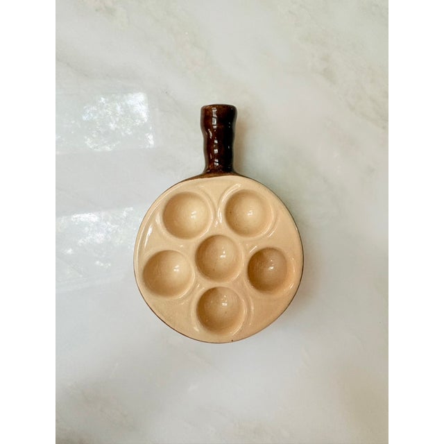 Small ceramic escargot serving dish with six wells, brown exterior glaze and cream interior glaze, hollow handle for...