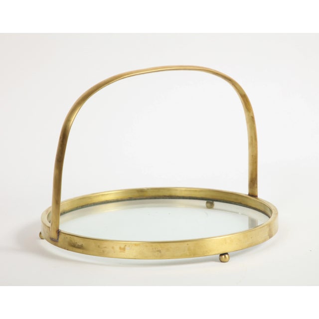 Midcentury brass and glass tray with handle and three ball-shaped feet.