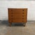 A compact Danish teak chest from the 1960s with five wide drawers and sculpted circular pulls. The repeated rings bring a...