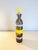 Bottle with a flared neck in clear green glass decorated with horizontal bands in yellow and gray. Spherical yellow...