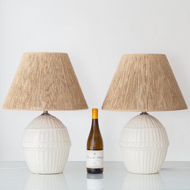 A pair of 1970s spanish ceramic table lamps crisply glazed in white and modeled in a convincing faux-wicker pattern; the...