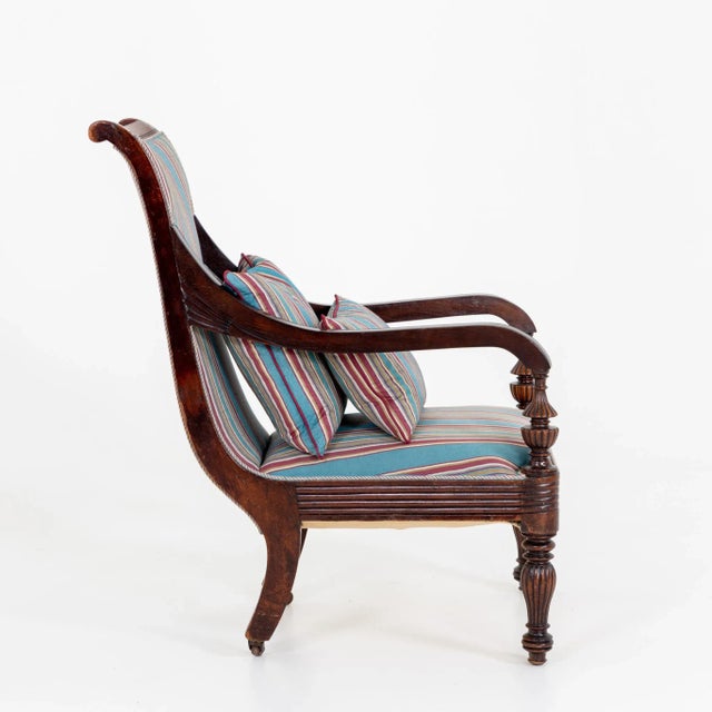 English mahogany armchair with striped upholstery. The rear legs are on brass castors.
