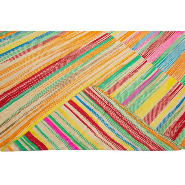 Beautiful modern Kilim flat-weave wool rug with a beige field. This piece of art has bright multicolor in a gorgeous...