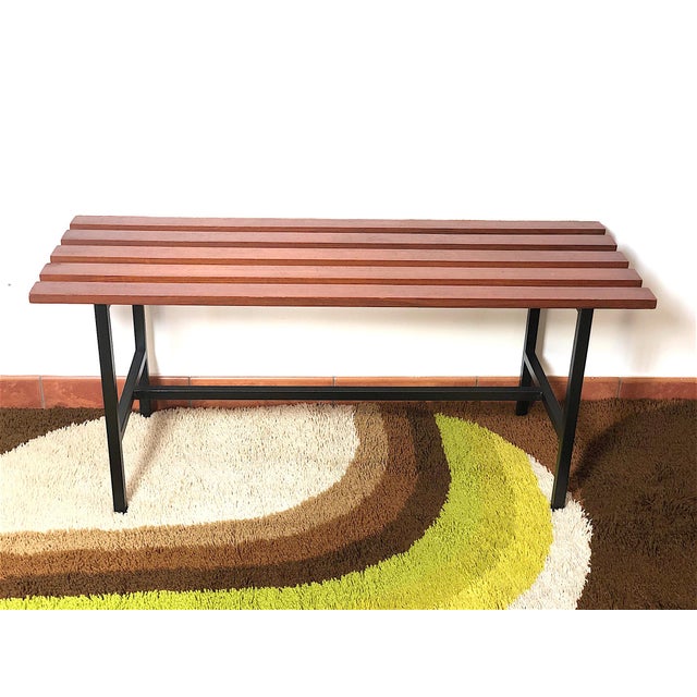 Vintage teak wood bench from the 1960s, made in Italy. The bench is made with 5 teak slats, a metal frame, and has been...