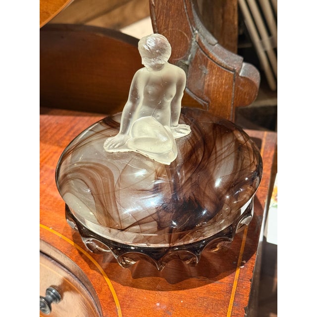 A beautiful antique glass jewelry box made by Thomas Davidson of England, dated 1922, featuring an elegant sculpted figure...