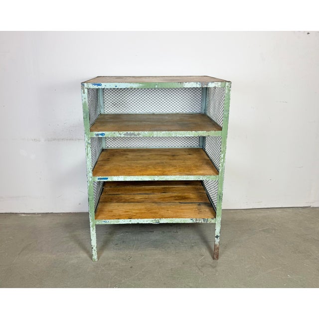 Industrial shelf from the 1960s. It features a green iron construction with iron mesh sides and back and four wooden shelves.
