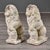 This matched pair of cast stone garden lions depicts each figure seated with one forepaw resting on a shield bearing a...