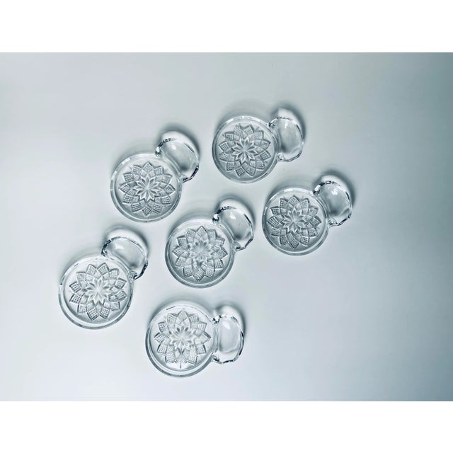 A classic set of pressed glass coasters in a textured starburst radiant design with attached spoon rest made by the...