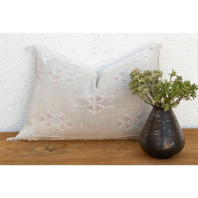 Two stacked diamond medallions rest side by side at the center of this handcrafted Moroccan cactus silk lumbar pillow,...