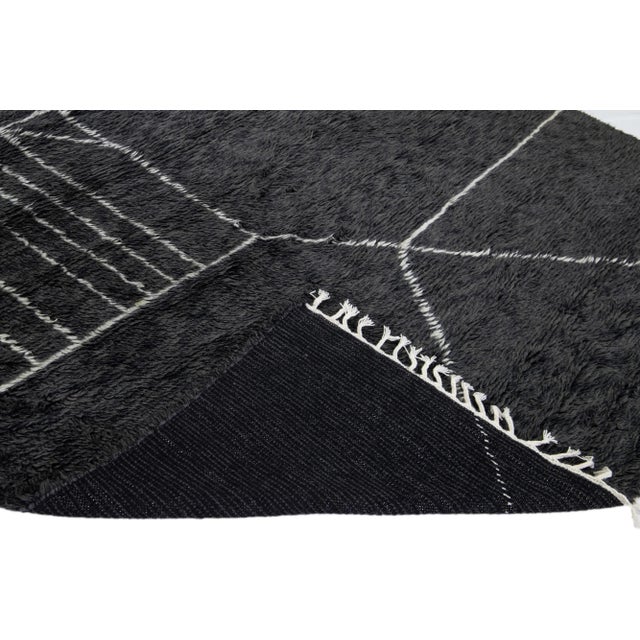 Beautiful modern Moroccan style hand-knotted wool rug with a black field and white fringes in a gorgeous geometric...