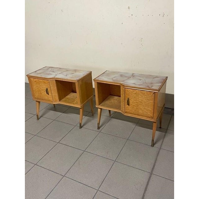 A pair of Italian-made 1960s nightstands featuring an elegant maple burl veneer and a marbled glass top. The wooden frame...
