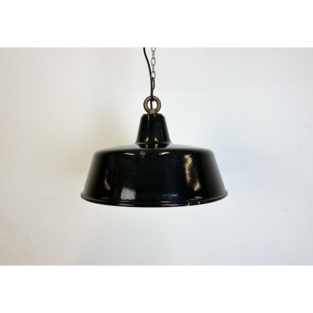 Industrial black enamel pendant lamp with white interior. Iron top. Manufactured during the 1950s. New porcelain socket...