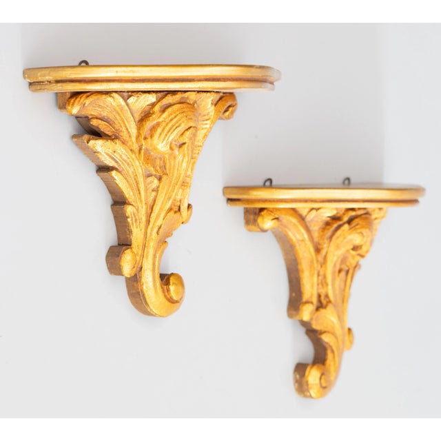 A lovely pair of vintage Italian gilded wood and gesso wall brackets shelves, circa 1950. These stunning brackets are...