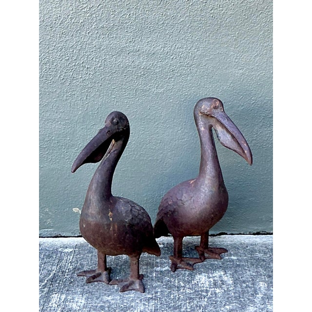 This charming pair of vintage wrought iron pelican statues is a masterful celebration of coastal artistry and rustic mid-...