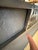 This mirror features a dark gray metal frame with prominent geometric square textured pattern with pyramid details.