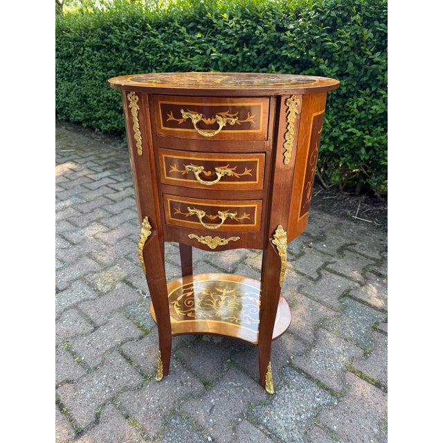 A refined pair of 1960 French Louis XVI-style mahogany commodes, richly decorated with marquetry inlay and gilded bronze...