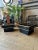 A pair of continental square black lacquered and brass trimmed low end or side tables on floating bases. The brass trim...