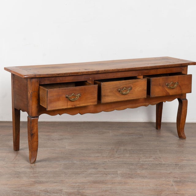 19th century French console table, crafted in cherry with three drawers across the front, each fitted with a large brass...