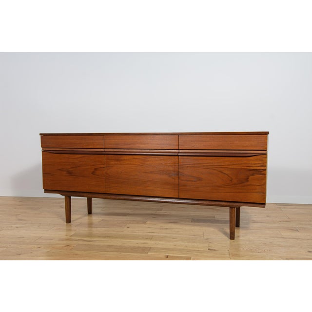 This mid-century sideboard in teak was produced in Great Britain by White & Newton in the 1960s. The sideboard has...