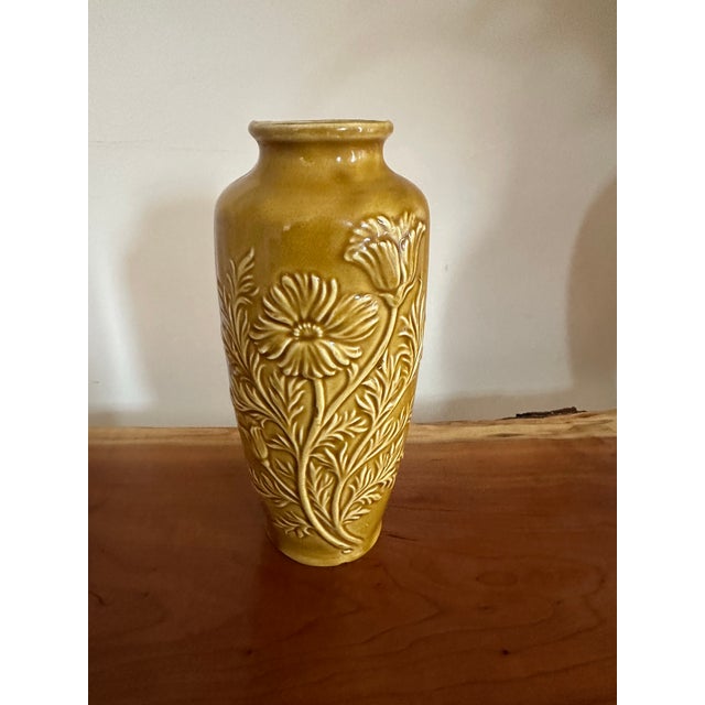 A striking vintage ceramic vase in a warm mustard yellow glaze, featuring an elegant embossed floral motif. The raised...