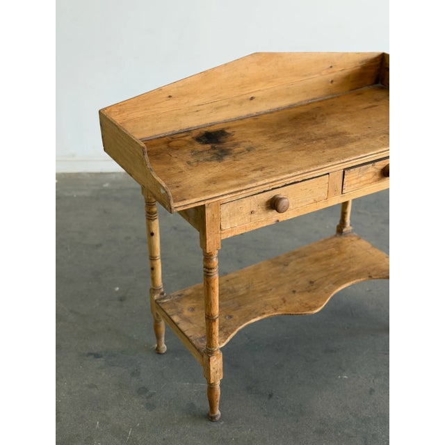 W42 D18 H39 This antique solid pine console table features two small drawers with wooden knobs, and delicate turned legs....