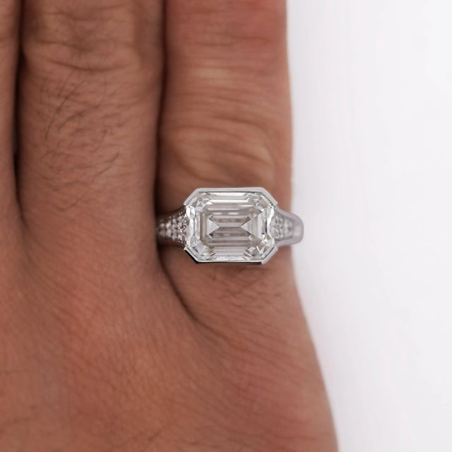 Lab-grown east-west set 5.32 carat emerald cut diamond in half bezel setting with white diamond accents in 14K white gold...