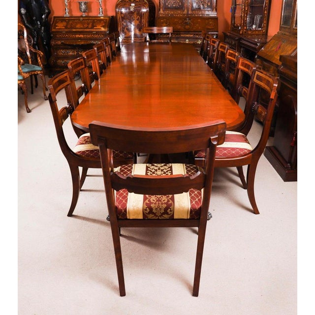 This is an elegant vintage dining set that comprises a Regency Revival triple pillar dining table and a set of sixteen...
