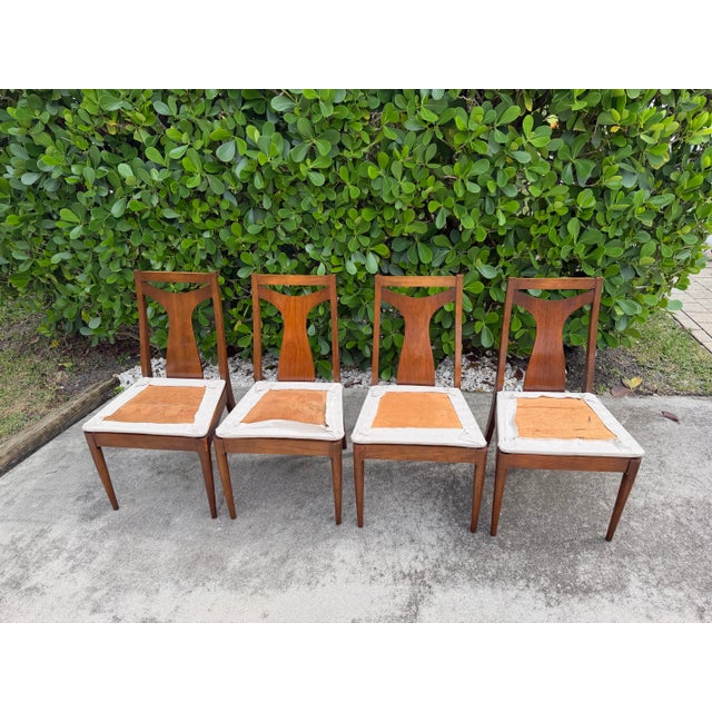 Vintage mid-century walnut dining chairs featuring distinctive sculpted backrests, tapered legs, and warm walnut tones....