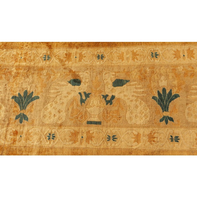 An early 20th century Indian antique rug, the open tan field within a camel exotic bird and vase border with indigo...