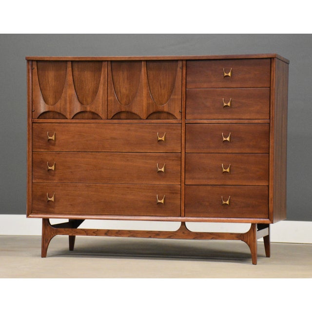 A mid century modern walnut eight drawer dresser credenza with swooping walnut and brass arch details made by Broyhill...