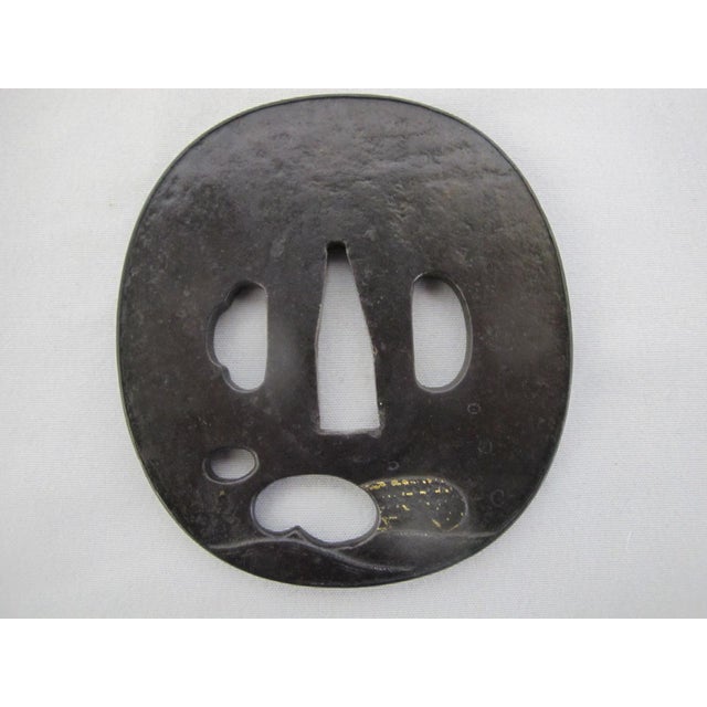 Antique Japanese hand forged iron Tsuba. Features a detailed wave design in gold for decorative elements, which was common...