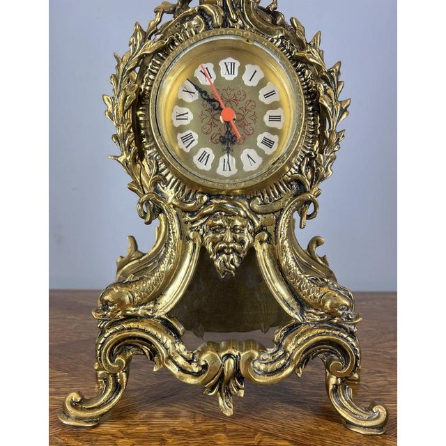 This Vintage French mantel clock is an eye-catching decorative piece, richly detailed with sculptural elements and an...