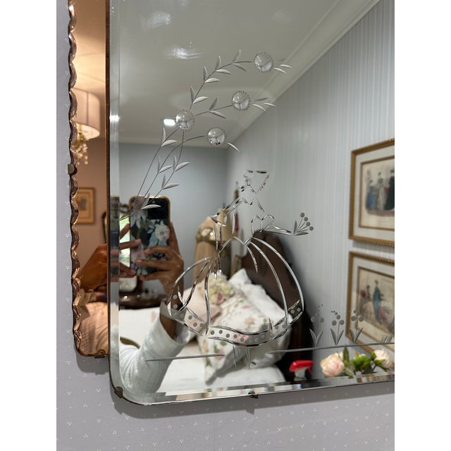 Charming and highly decorative Art Deco wall mirror featuring a beveled central mirror plate with an etched figural design...