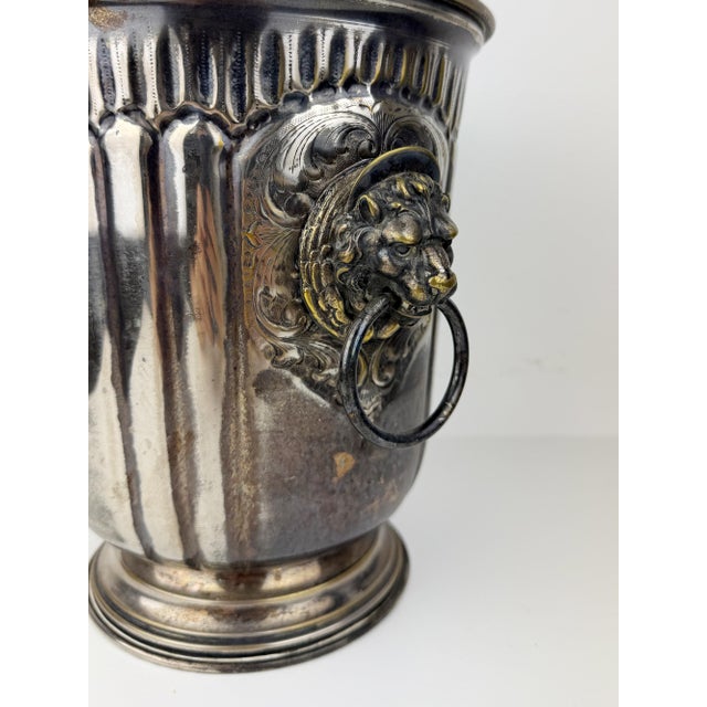 Antique silver-plated champagne bucket featuring beautifully detailed lion head ring handles, fluted sides, and embossed...