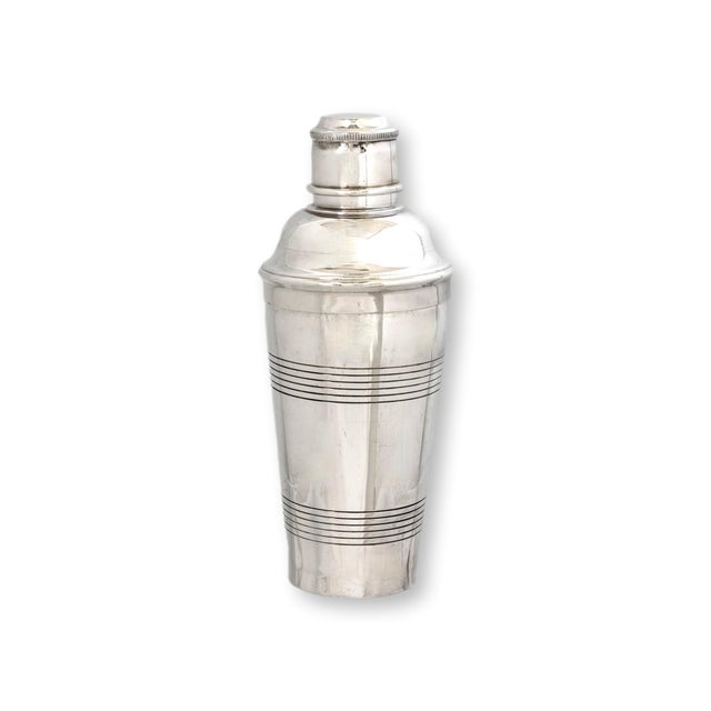 Early 20th century silverplate cocktail shaker featuring a classic traditional form with subtle horizontal banding and...