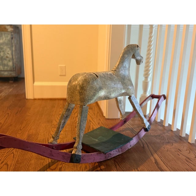 A charming antique hand-carved wooden rocking horse featuring a wonderfully weathered original painted finish and classic...