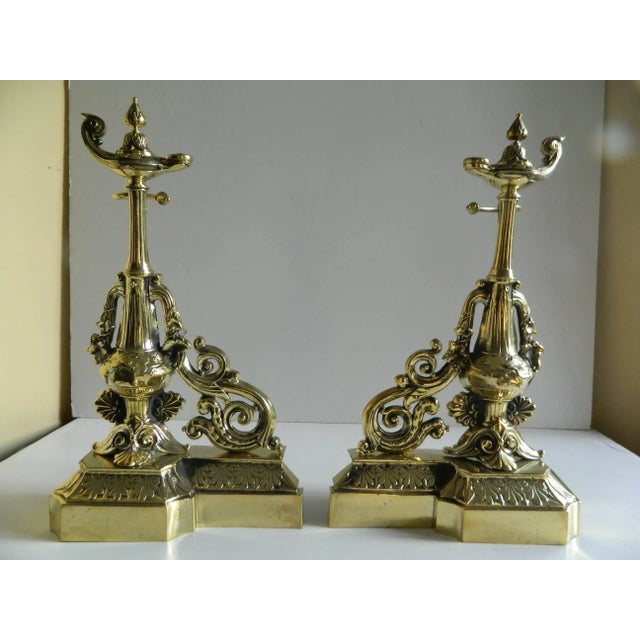 Pair of brass chenets or andirons, magical or oil lamp motif, 19th century.