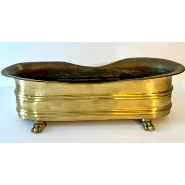 Elongated Rectangular Brass Jardiniere or planter with Lion Paw feet and a gentle curve to the front and rear sides. A...
