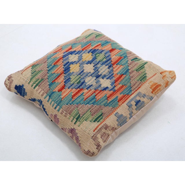 A one-of-a-kind handwoven Afghan wool kilim accent pillow featuring rows of stepped diamonds in blue, red, and green on...