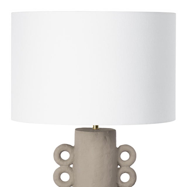 The primitive, vase-like, cast metal base of the Chandra Table Lamp is dappled with a natural, paper mache finish. A...