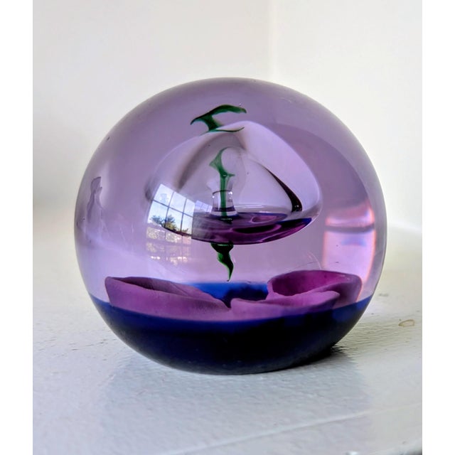 Glass paperweight made in Scotland, features a silver spaceship hovering above the moons craters. in a rich purple color