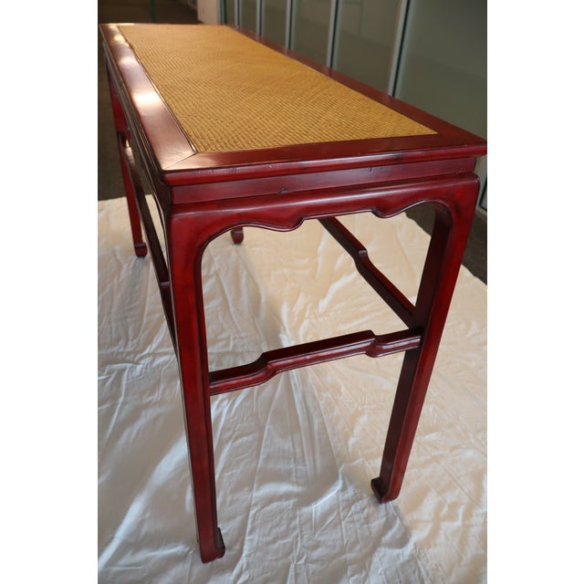 This stunning Swaim console table showcases a hand-rubbed cinnabar red finish with a natural woven raffia top, creating...