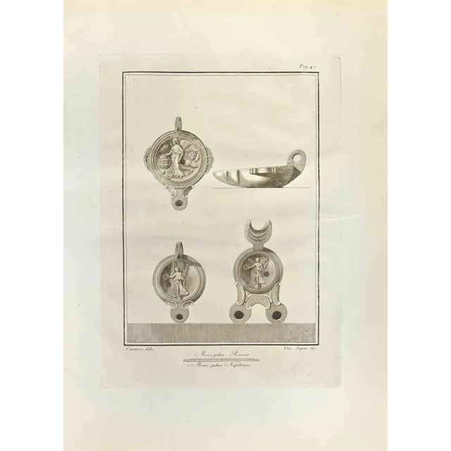 Pompeian Style Oil Lamps from "Antiquities of Herculaneum" is an etching on paper realized by Vincenzo Segoni in the 18th...