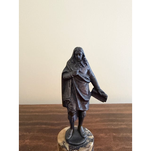 A Grand Tour–style classical figure in brass, mounted on a cylindrical marble base. The slightly more relaxed posture and...