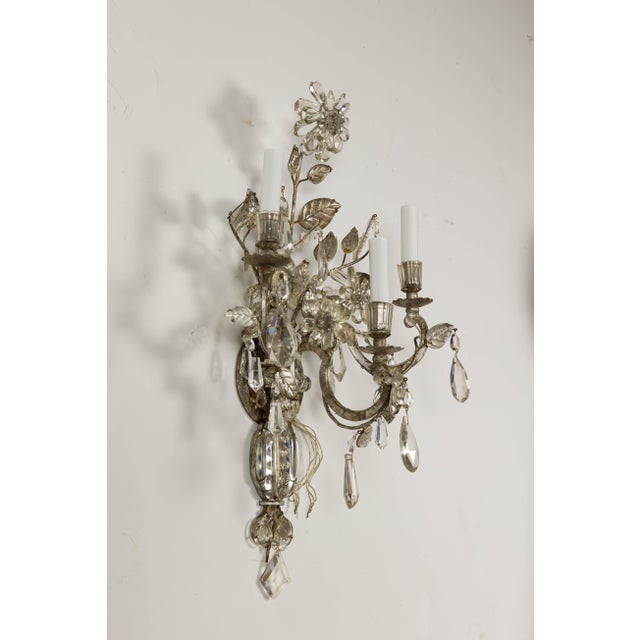 A pair of French Maison Baguès crystal sconces from circa 1940 with three arms each and floral motifs. Embodying the...